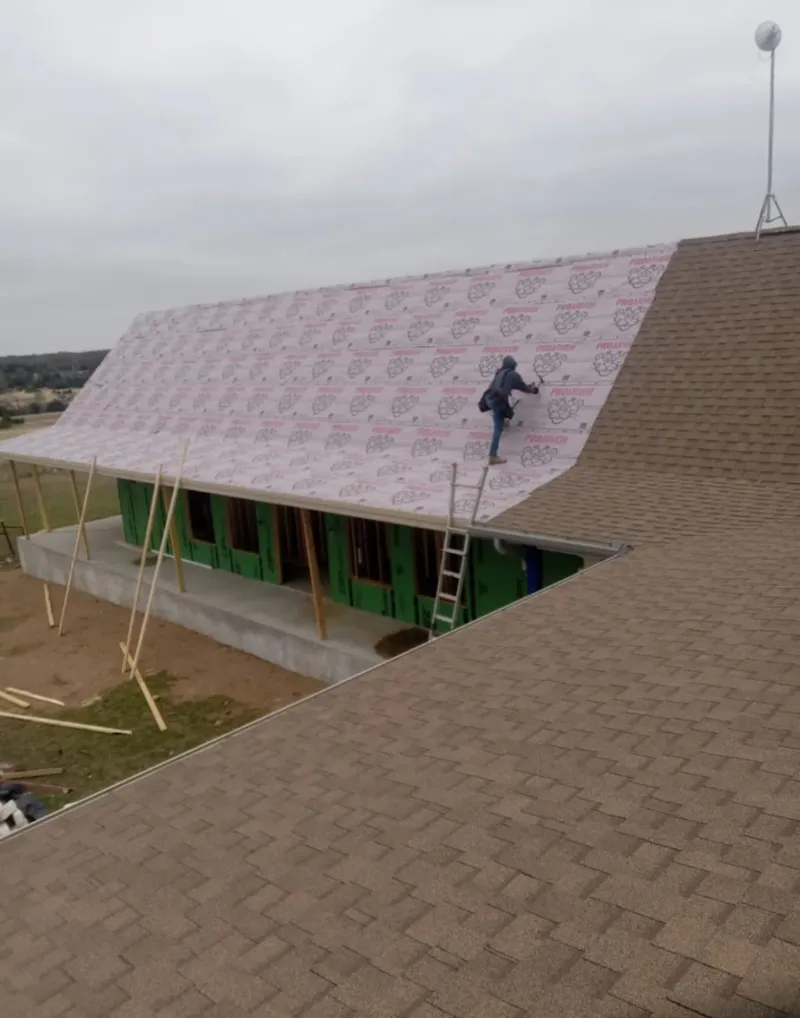 Worker preparing underlayment for a metal roof installation in Medina